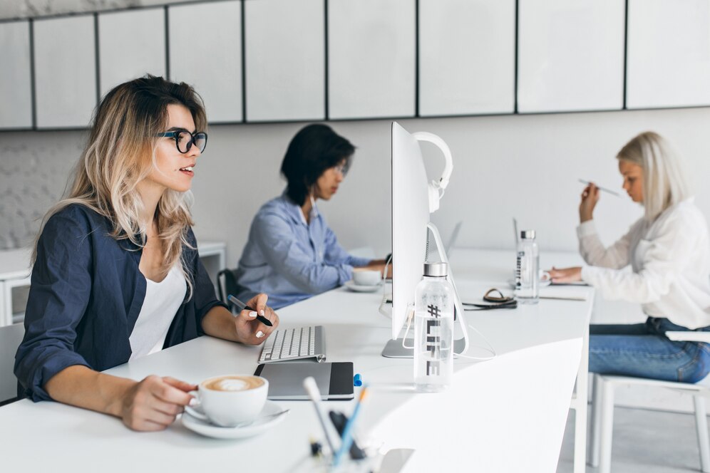 surprised-blonde-woman-looking-computer-screen-enjoying-latte-her-workplace_197531-4961